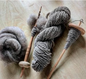 image shows hand spun yarn and a drop spindle